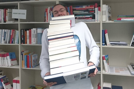 Kai Schreiweis mit einem Stapel Bücher
