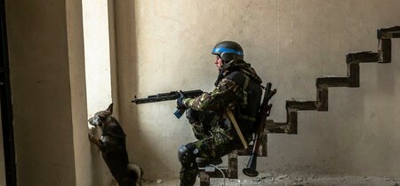 Ukrainischer Soldat mit Gewehr in einem Haus am Fenster