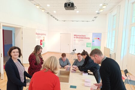Das Team der Landeszentrale beim Packen von Postkarten im Ausstellungsraum der Landeszentrale.