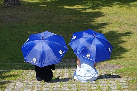 2 Menschen sitzen unter blauben Schirmen