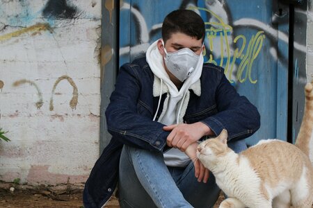 einsamer Jugendlicher mit Corona-Maske und Katze