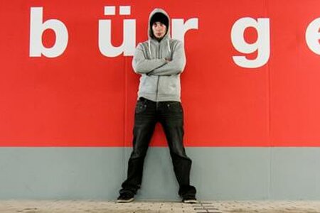 Jugendlicher vor einer Wand mit der Aufschrift "Bürger"
