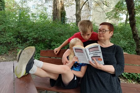Martina Weyrauch und zwei Kinder schauen in das Buch "Deutschland 2050"