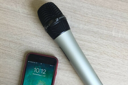 Ein Smartphone und ein Mikrofon liegen auf einem Tisch. 
