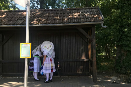 Zwei Frauen in sorbischer Tracht warten an einer Bushaltestelle