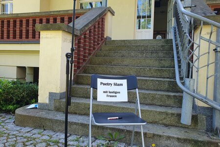 Poetry Slam in der Landeszentrale: Ein Stuhl mit der Ankündigung steht auf der Treppe vor dem Eingang