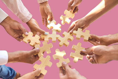 Viele Hände halten Puzzleteile