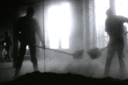 Schwarz-weiße Silhouetten von zwei Personen, die mit Schaufeln in einem nebligen oder staubigen Raum arbeiten.