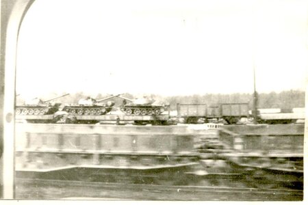 Aufnahme aus einem Zug heraus. Zu sehen ist ein Teil des Verladebahnhofes mit Panzern
