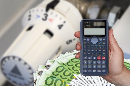 eine Hand mit Taschenrechner vor der Heizung