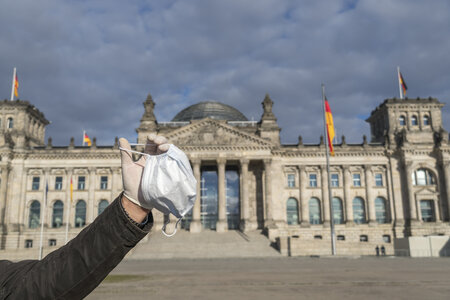 Mit einer Corona-Maske vor dem Bundestag
