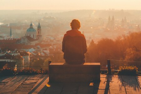 Eine Person sitzt allein auf dem Dach über einer großen Stadt