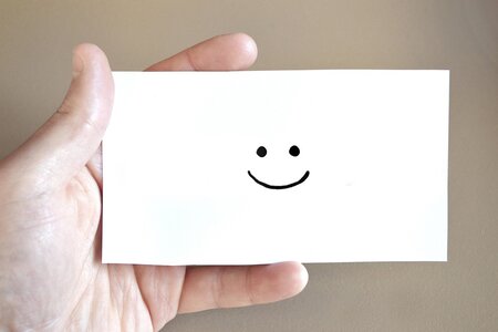 Eine Hand hält einen Brief mit einem freundlichen Smiley