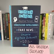 Im Hintergrund eine Reihe Bücher. Im Vordergrund das Buch" Künstliche Intelligenz - Fake News - Unsere digitale Zukunft" von Manfred Theisen.