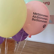 Bunte Luftbalons. Eine trägt die Aufschrift "MitStimmen, AbStimmen, BeStimmen"