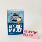Das Buch "Die geteilte Stadt - Berliner Mauer" von Christian Bahr steh vor weißen Hintergrund. Daneben steht ein Zettel mit der Aufschrift "Aus unserem Buchshop". 