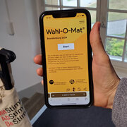 Eine Hand hält ein Smartphone.  Das Display des Smartphones zeigt den Wahl-O-Mat zur Landtagswahl in Brandenburg.