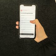 Veranstaltungskalender Politische Bildung. Eine Hand hält ein Handy, auf dem die Suchfunktion des Kalenders dargestellt ist. 