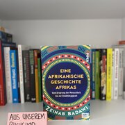Im Hintergrund eine Reihe Bücher. Im Vordergrund das Buch „Eine afrikanische Geschichte Afrikas“ von Zeinab Badawi. 