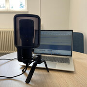 Ein Mikrofon und ein Laptop stehen auf einen Tisch. 