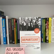 Im Hintergrund eine Reihe Bücher. Im Vordergrund das Buch „Deportiert“ von Andrea Löw. 