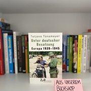 Im Hintergrund eine Reihe Bücher. Im Vordergrund das Buch „Unter deutscher Besatzung. Europa 1939-1945“ von Tatjana Tönsmeyer. 