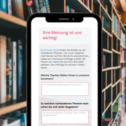 Im Hintergrund ein Bücherregal. Im Vordergrund ein Smartphone. 