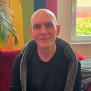 Christian Müller sitzt auf einer Couch. 