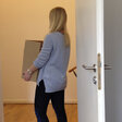 Die Praktikantin geht mit einer Kiste Habseligkeiten aus der Tür