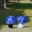 2 Menschen sitzen unter blauben Schirmen
