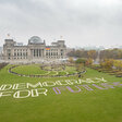 Die Demokratie der Zukunft wird von und mit uns allen gestaltet. Eine große Spirale vor dem Reichstag – geformt aus goldglänzendem Stoff und Hunderten von Menschen – greift die Form der Reichstagskuppel auf. Sie bildet eine Brücke von den Menschen auf der Wiese zu den Menschen im Bundestag. Das Motto: "Democracy for Future."