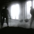 Schwarz-weiße Silhouetten von zwei Personen, die mit Schaufeln in einem nebligen oder staubigen Raum arbeiten.