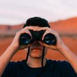 Mann mit Fernglas blickt Richtung Zukunft