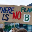 Eine Person hält ein Schild mit "There is no Planet B