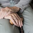 Das Foto zeigt die Hände von einem alten Mann mit Krückstock