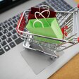 Ein Einkaufswagen mit Tüten auf einer Tastatur vor dem PC