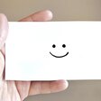 Eine Hand hält einen Brief mit einem freundlichen Smiley