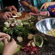 viele Hände schnippeln Gemüse an einem Tisch